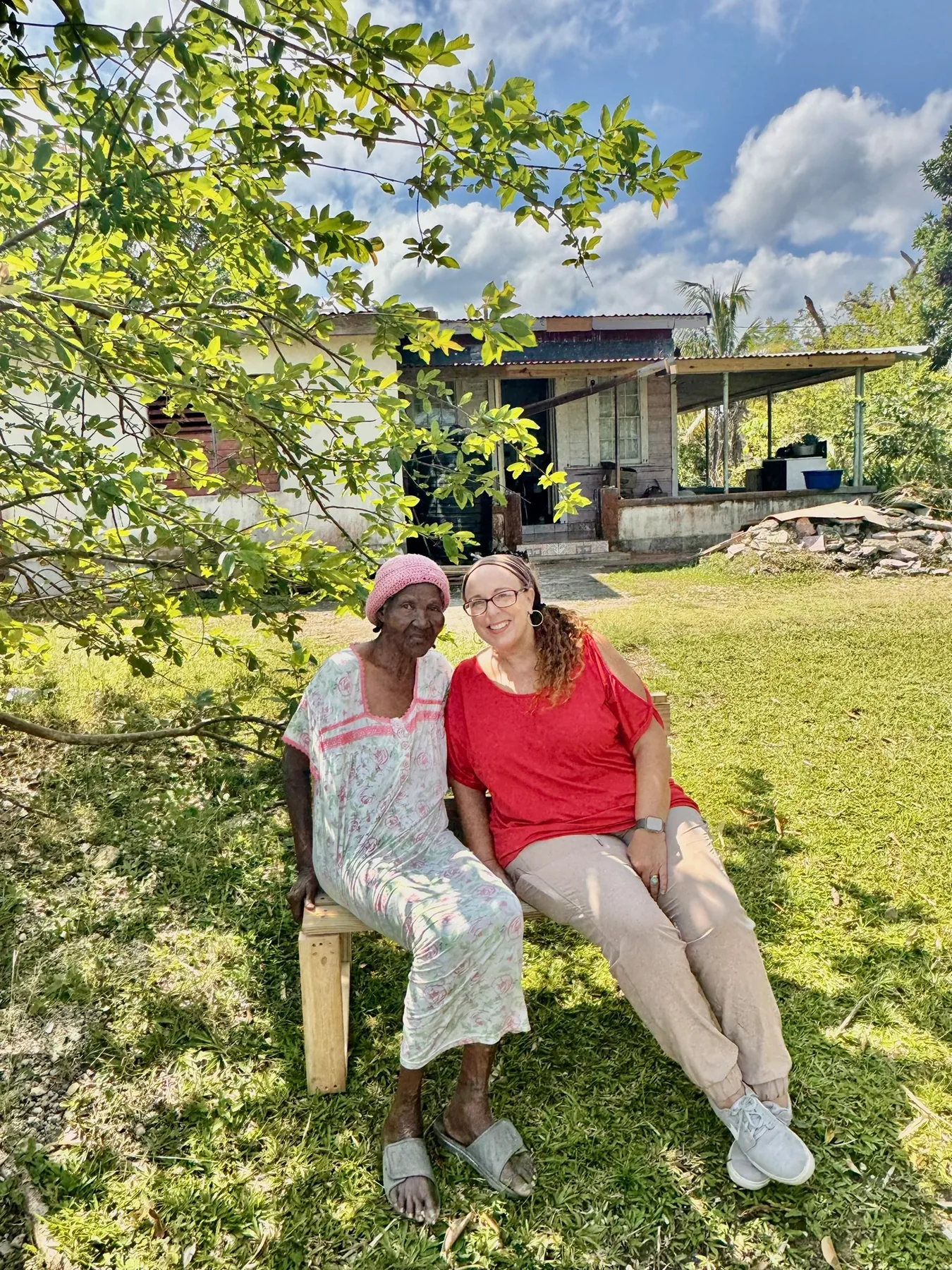 Kat Weir sitting outdoors with a woman during a community visit
